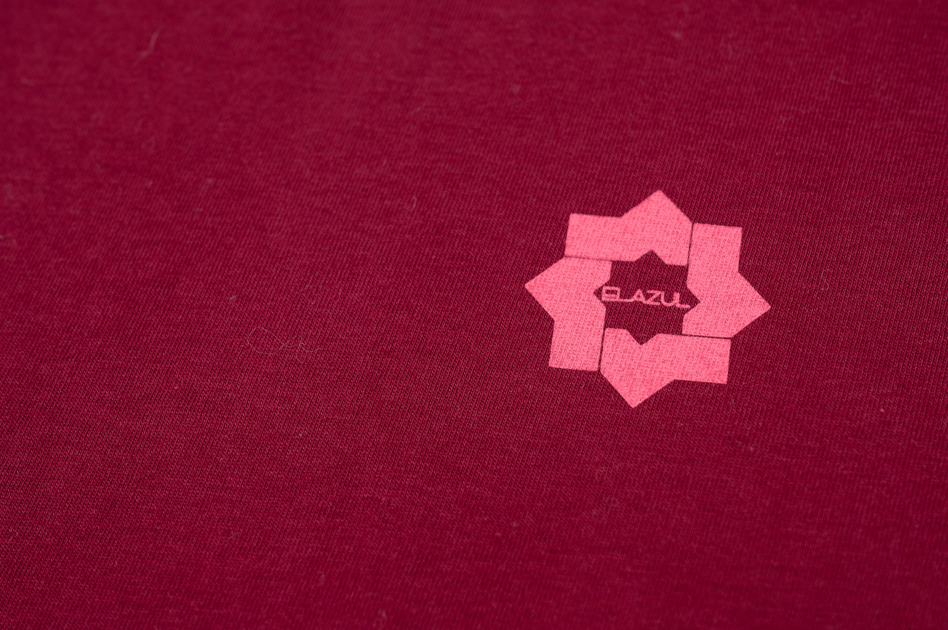 Detalle de logo rosa en pecho sobre camiseta de manga corta unisex color burdeos